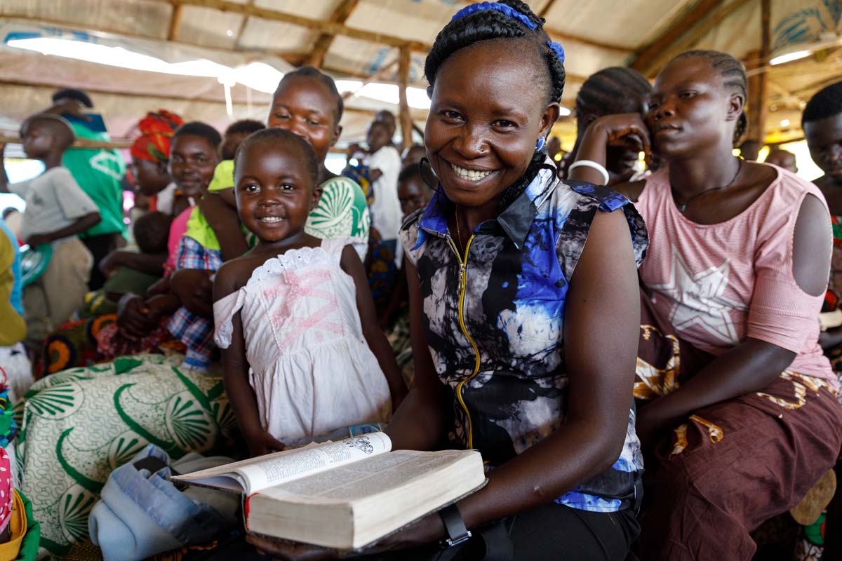 Uganda, woman with Bible in church seated with congregation